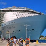 Allure of the Seas docked in Nassau under a bright blue sky, with passengers walking along the pier