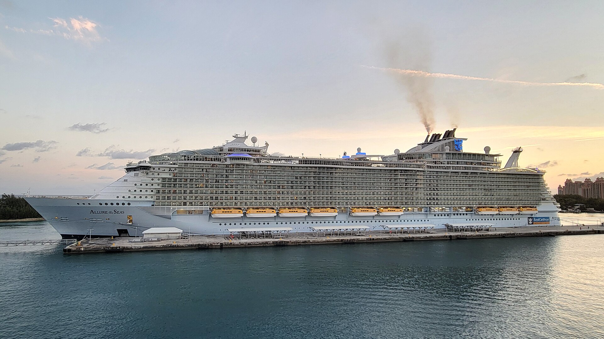 Allure of the Seas docked at Nassau Cruise Port under a pink and blue sunrise sky