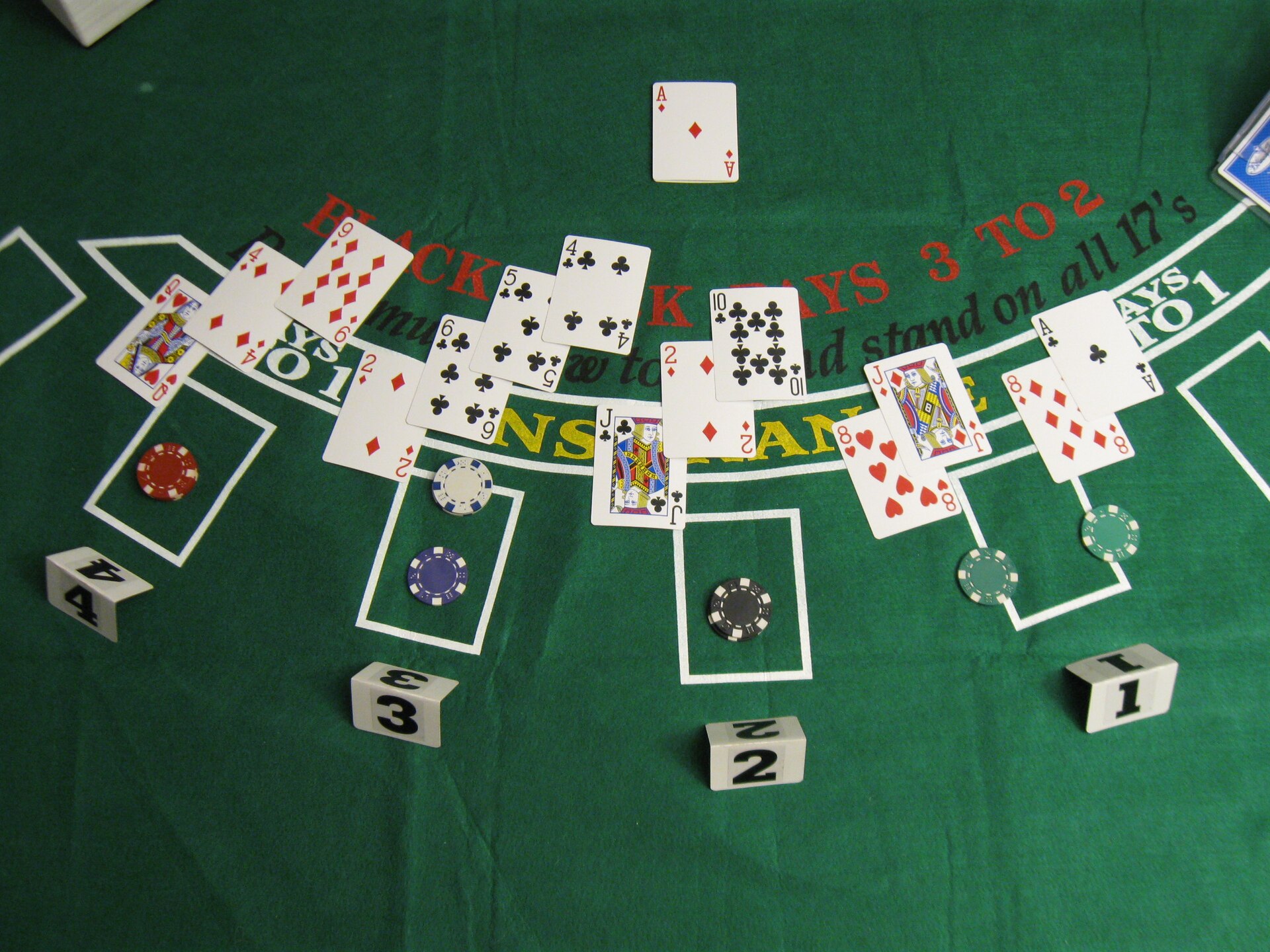 Blackjack hands dealt on green felt with chips and player position markers