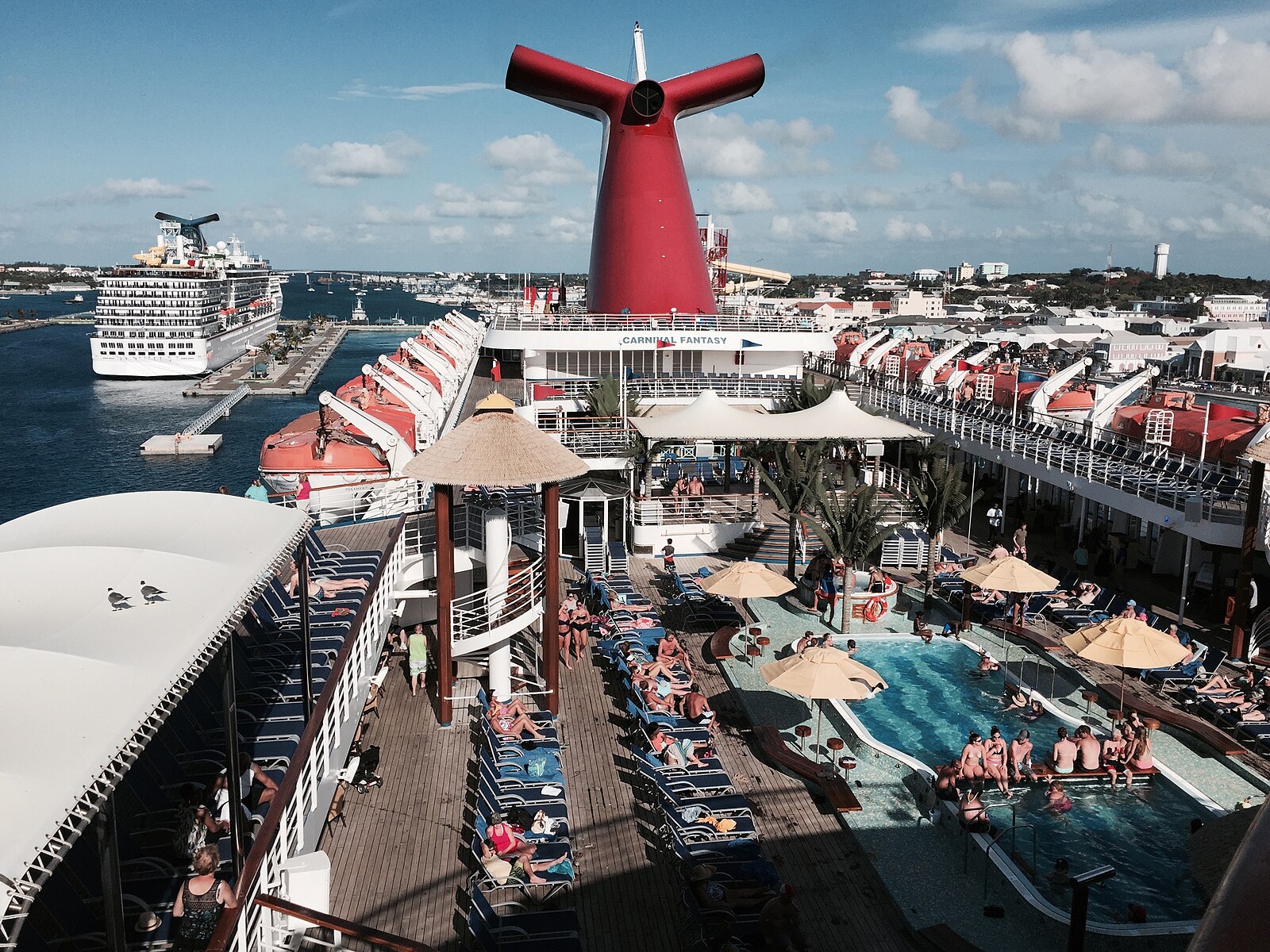 Carnival cruise ship Lido deck pool with red funnel, blue loungers and sun umbrellas