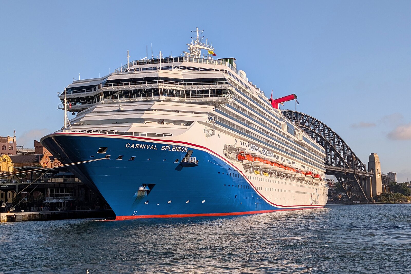 Carnival Splendor with her red white and blue hull alongside Sydney's Overseas Passenger Terminal under a clear sky