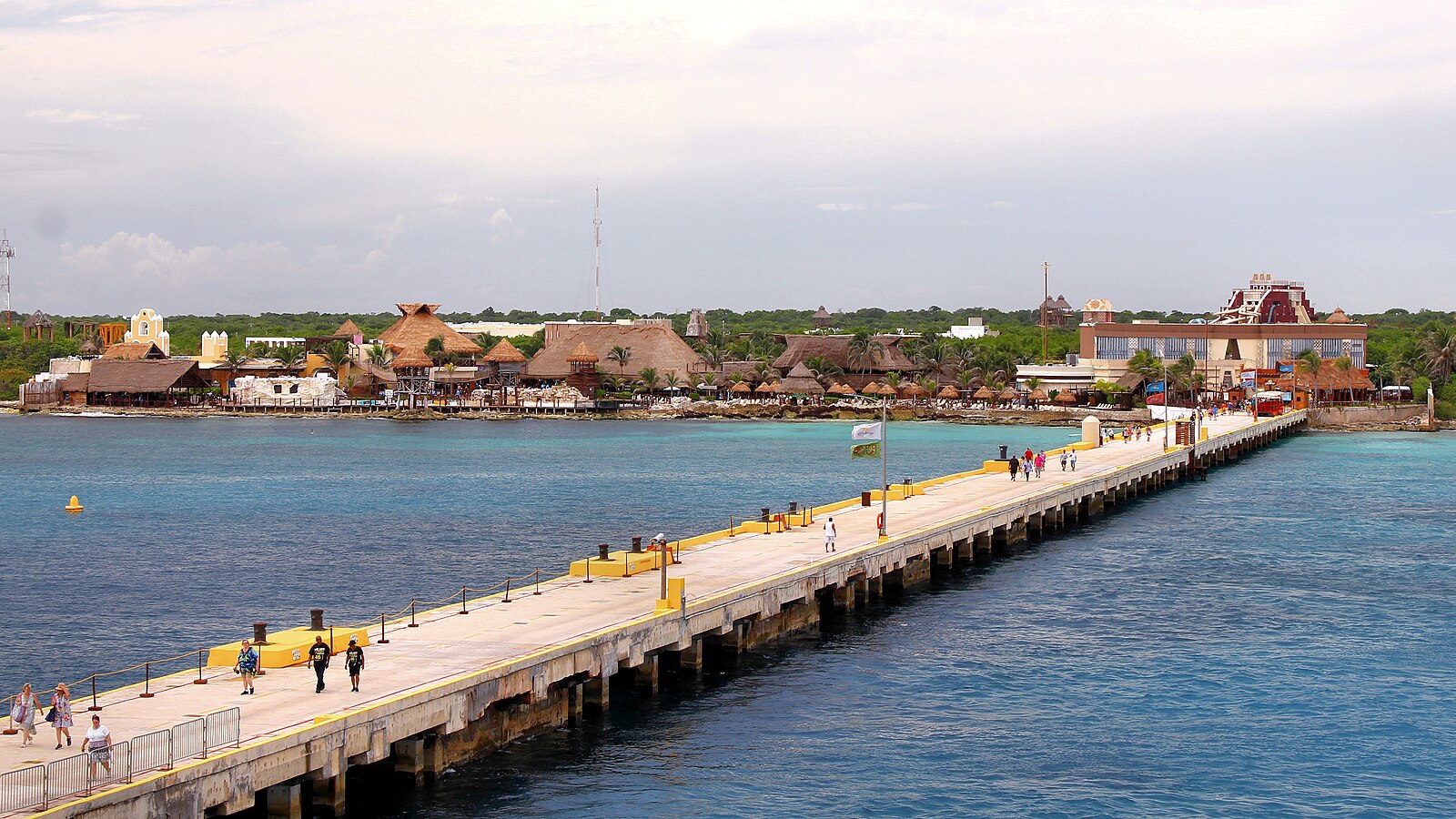 Long cruise pier over turquoise water leading to the palapa-roofed Costa Maya cruise port in Mexico