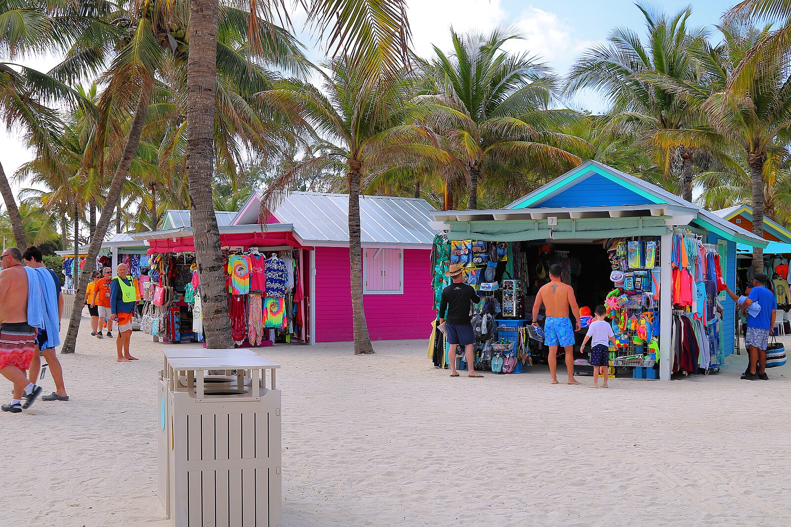 Brightly painted pink and turquoise beach shops among palm trees at Perfect Day at CocoCay in the Bahamas
