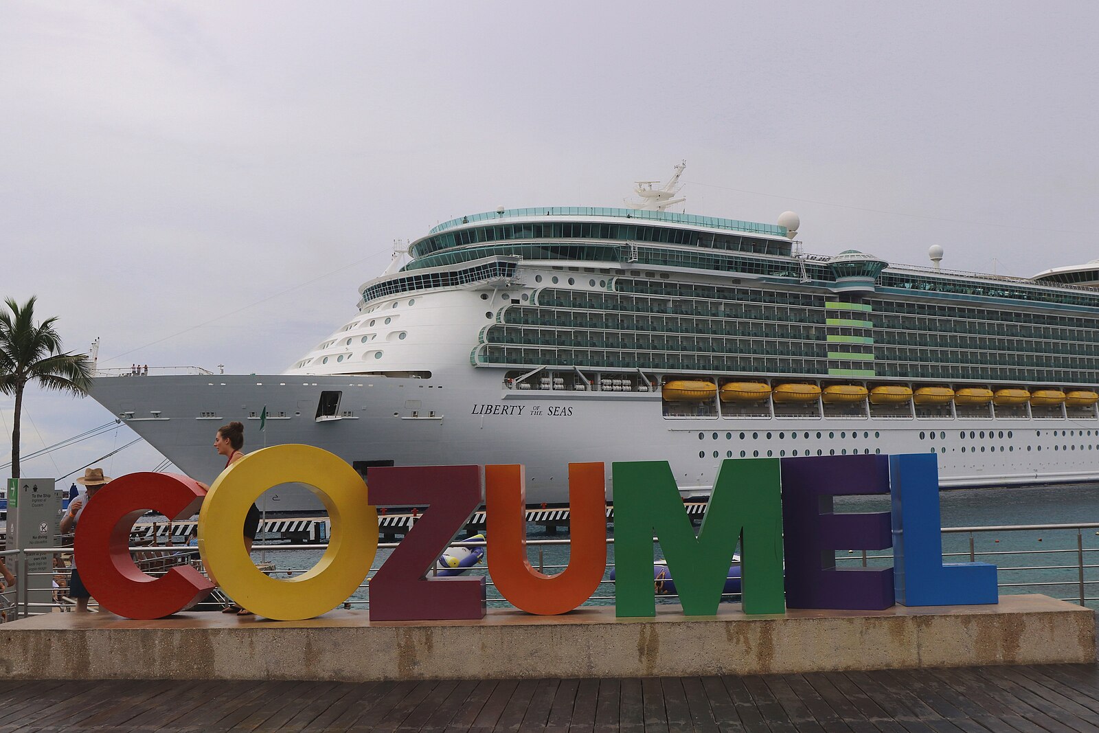 Colourful rainbow COZUMEL letters sign on the waterfront in front of Royal Caribbean's Liberty of the Seas