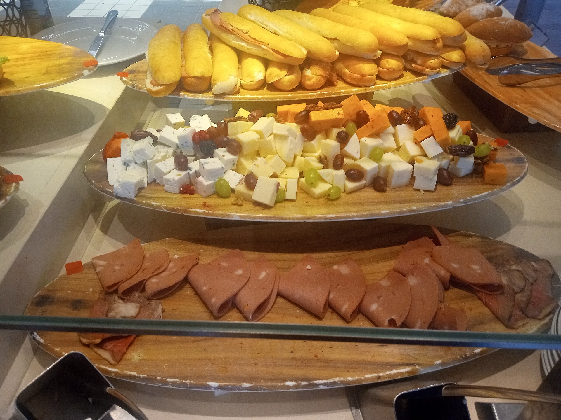 Cruise ship buffet deli counter with cubed cheeses, grapes, olives, sliced meats and filled rolls