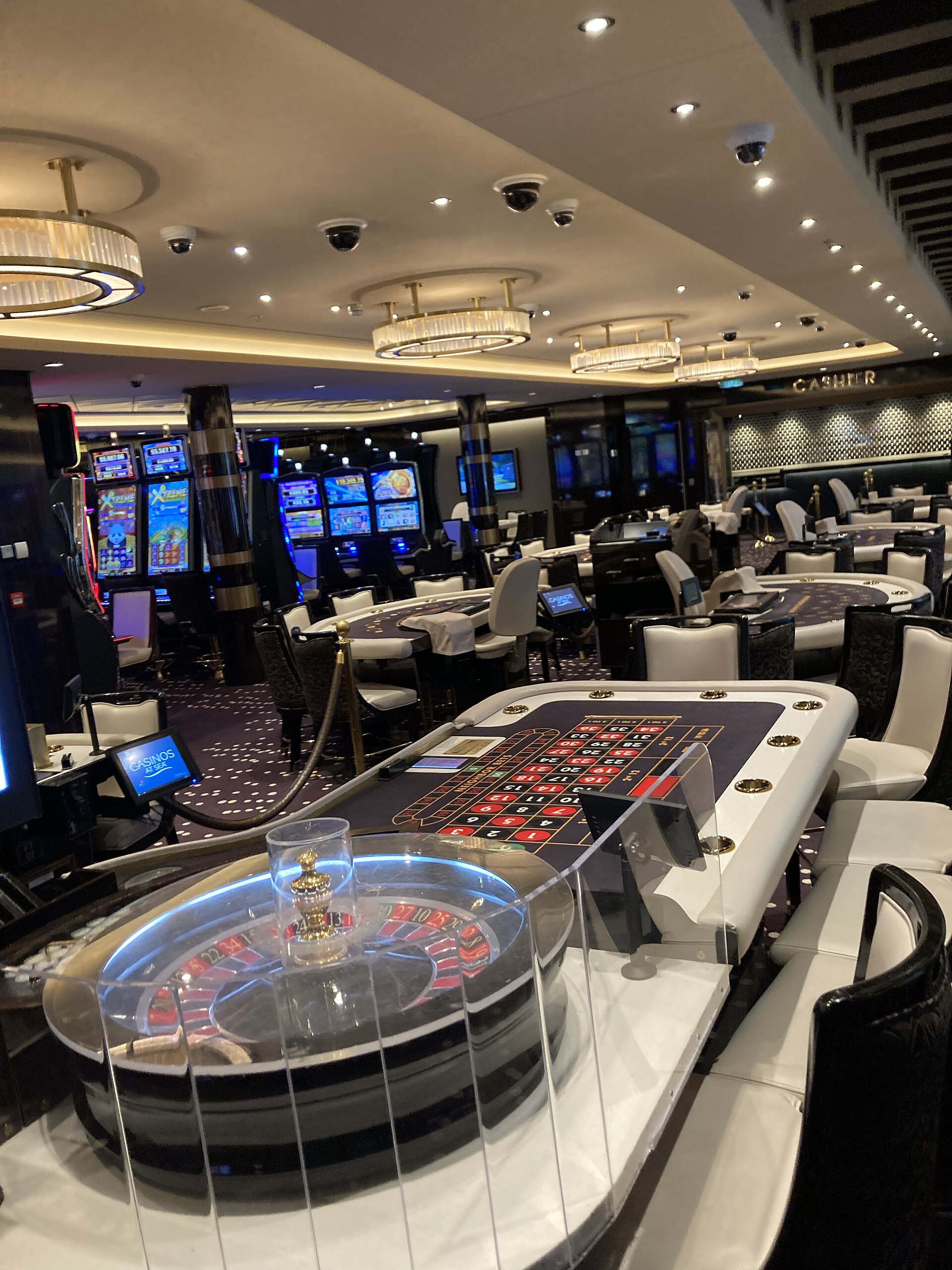 Roulette wheel and gaming tables in a brightly lit cruise ship casino