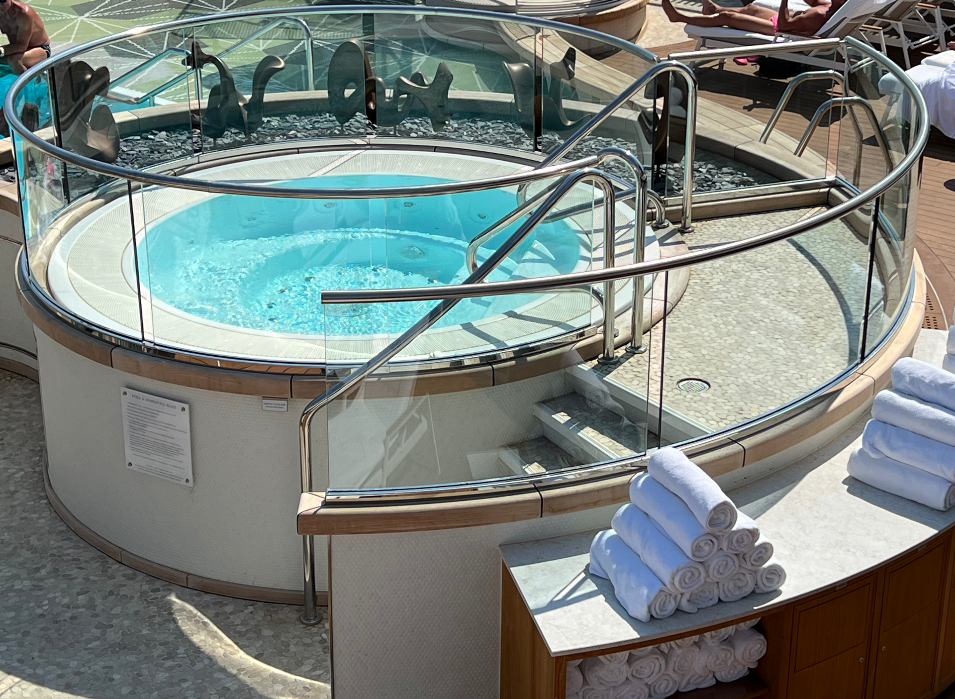 Turquoise hot tub on a cruise ship pool deck with stacked white towels