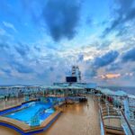 Cruise ship pool deck at sunset with the open ocean beyond
