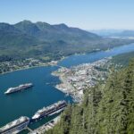 Four cruise ships in Juneau, Alaska, on a sunny day with deep blue water and green forested mountains