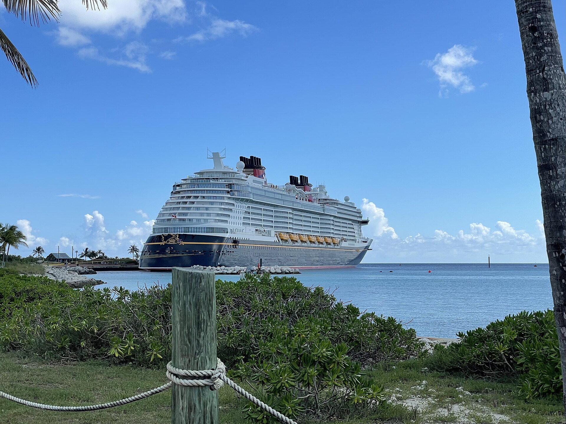 Disney Wish cruise ship docked at Castaway Cay with palm trees and turquoise water