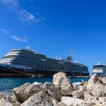 Holland America's Koningsdam docked at Willemstad, Curacao, under a deep blue sky, with Norwegian Epic behind