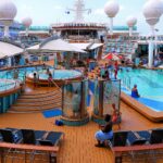 Busy pool deck on Royal Caribbean's Mariner of the Seas with swimmers, hot tubs and rows of sun loungers