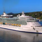 Royal Caribbean's Jewel of the Seas on bright blue water beside the green hills of Roatan, Honduras
