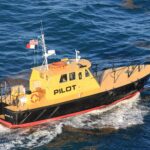 Yellow and black Miami pilot boat Vizcaya speeding across deep blue water beside a cruise ship