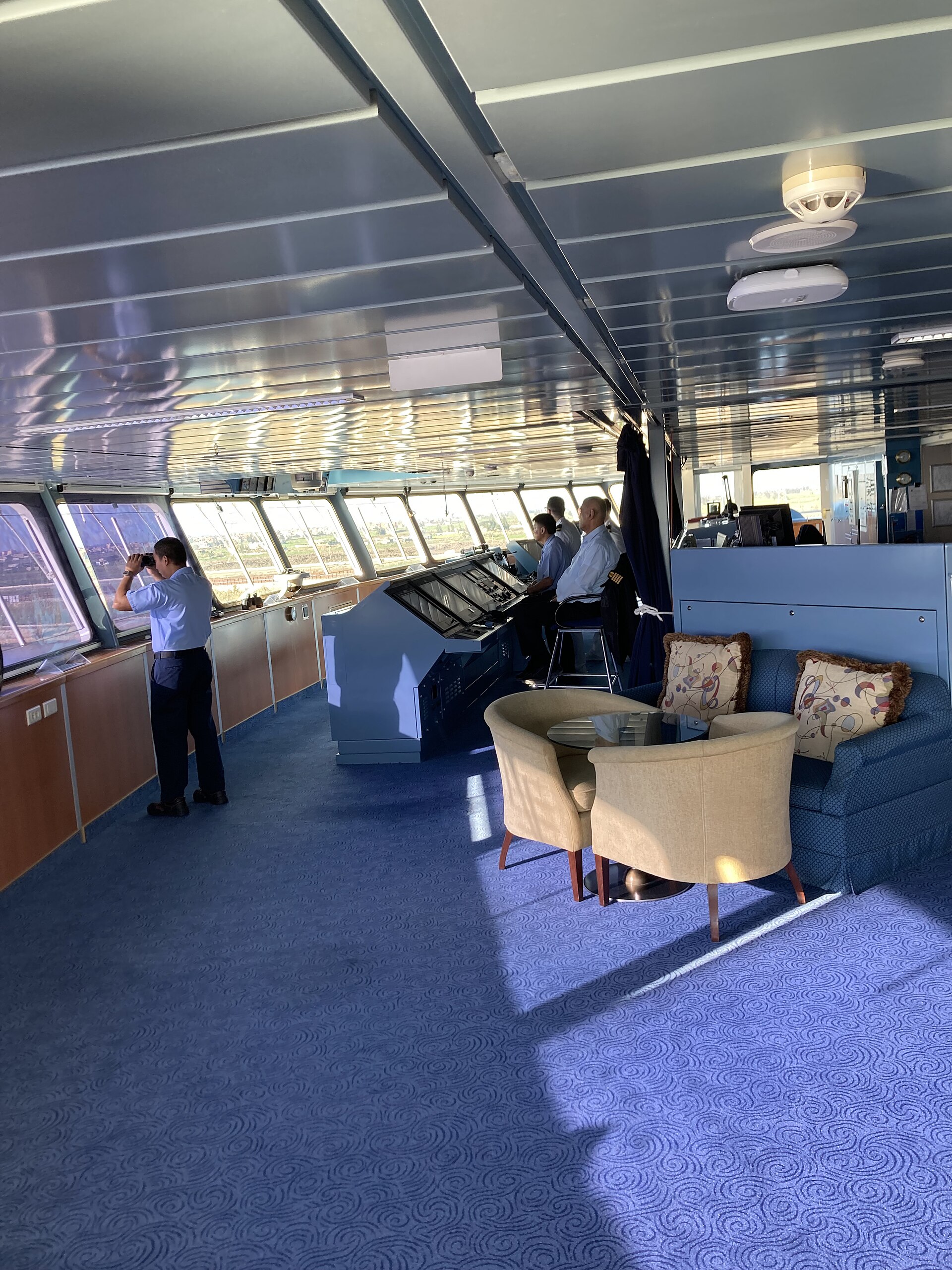 Officers on the sunlit bridge of a modern cruise ship