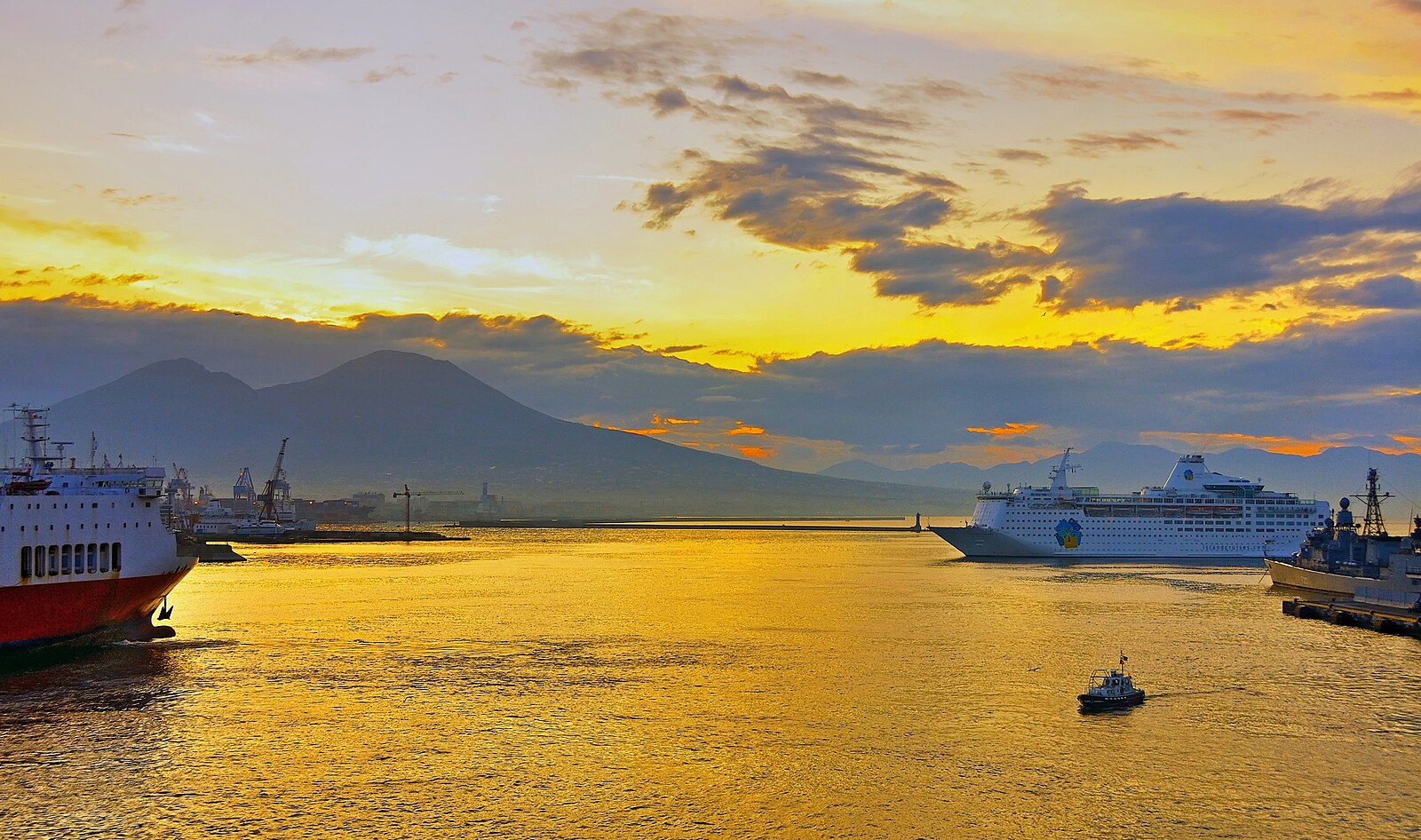 Golden dawn over the harbour of Naples with Mount Vesuvius behind and ships leaving port