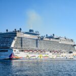 Norwegian Encore with its rainbow-painted hull sailing in bright blue water off Ogden Point, Victoria, British Columbia