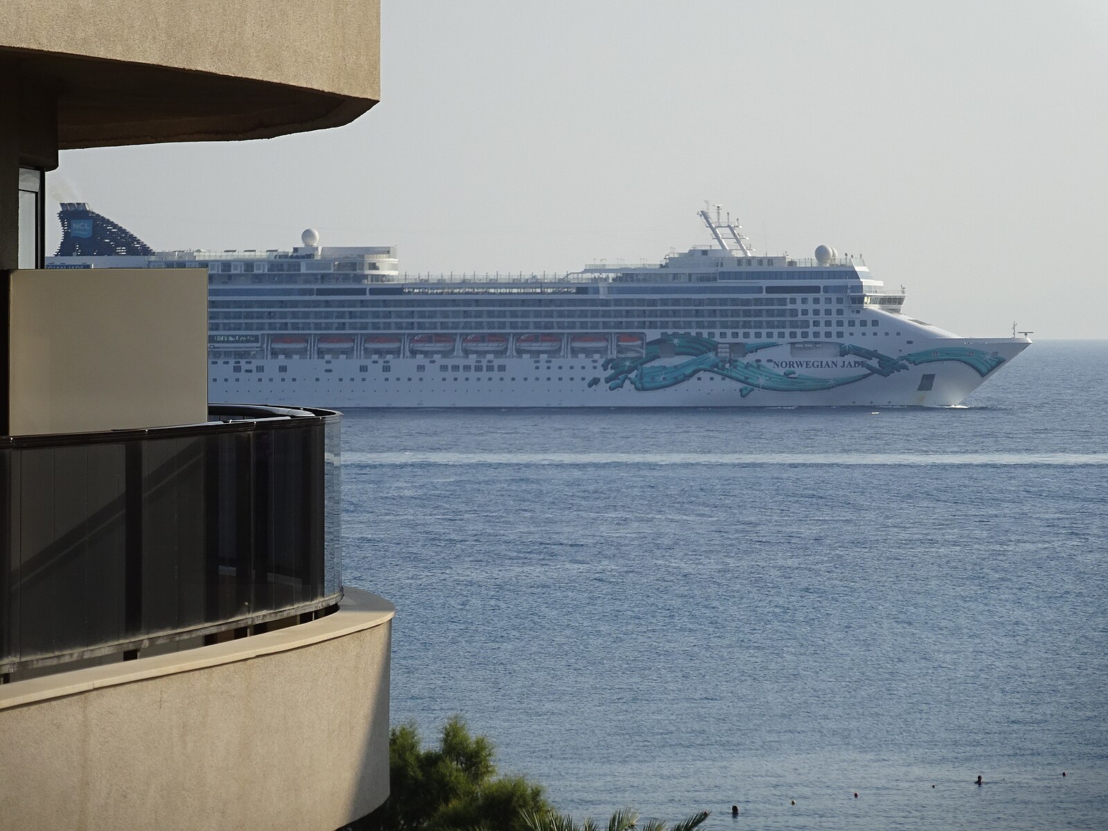 Norwegian Jade cruise ship with her teal hull artwork approaching the island of Rhodes
