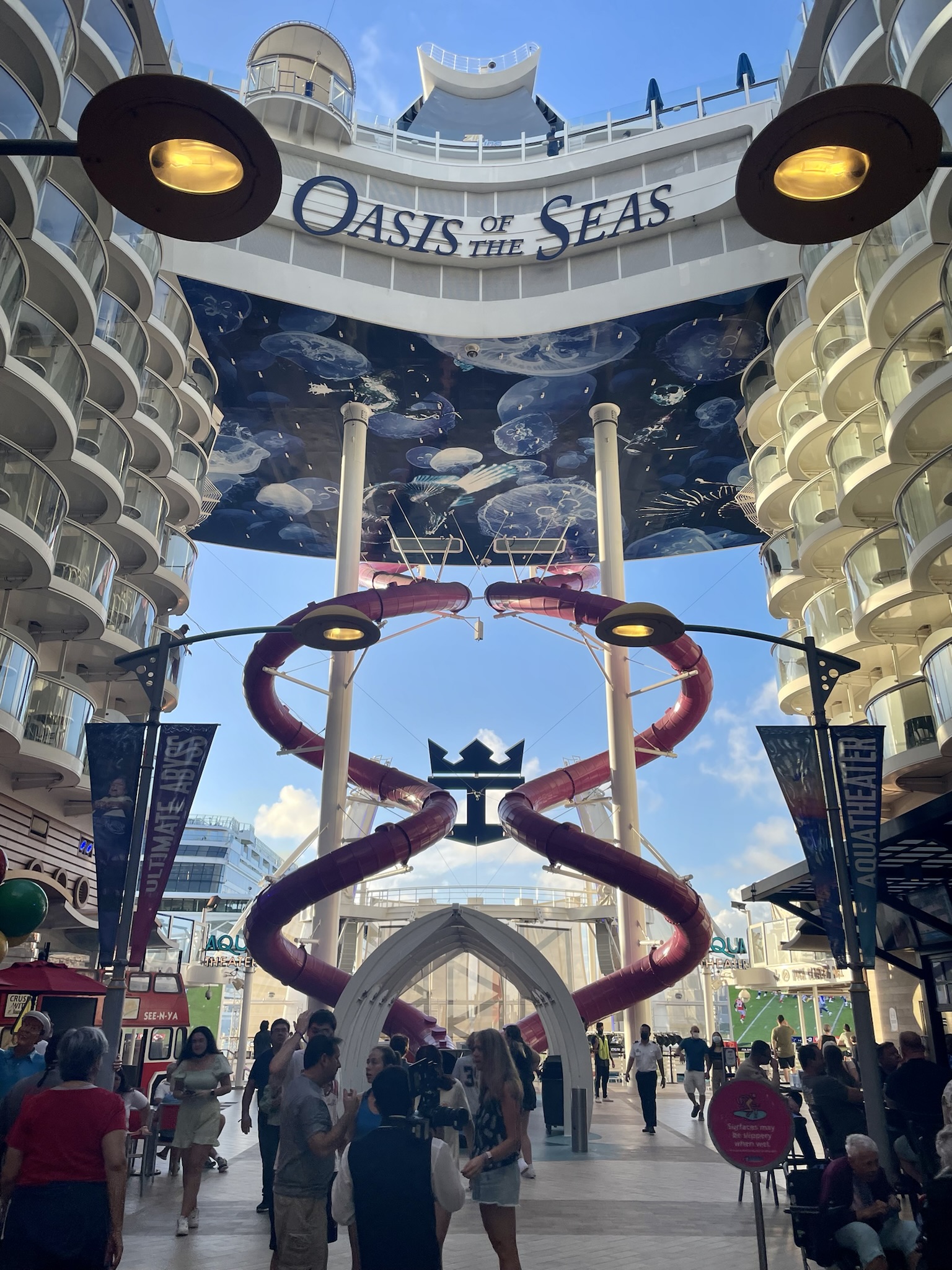 The Boardwalk on Oasis of the Seas with red corkscrew slides, balconies and a blue sky