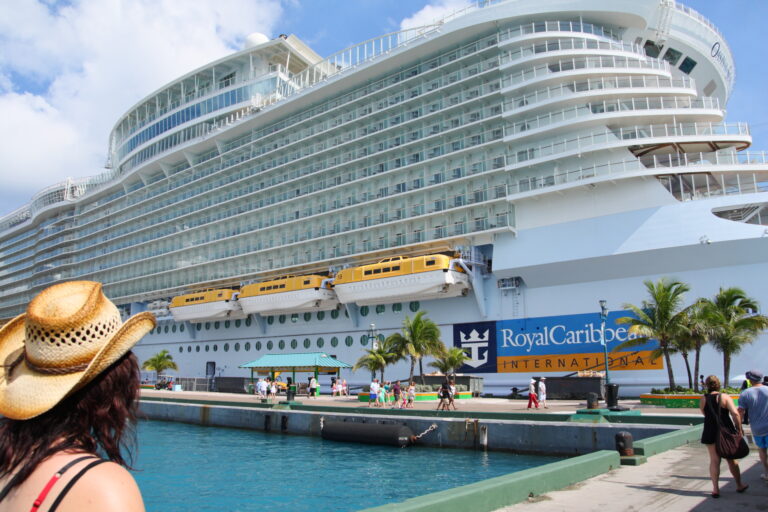 Royal Caribbean's Oasis of the Seas docked at the cruise pier in Nassau, Bahamas, with palm trees and turquoise water