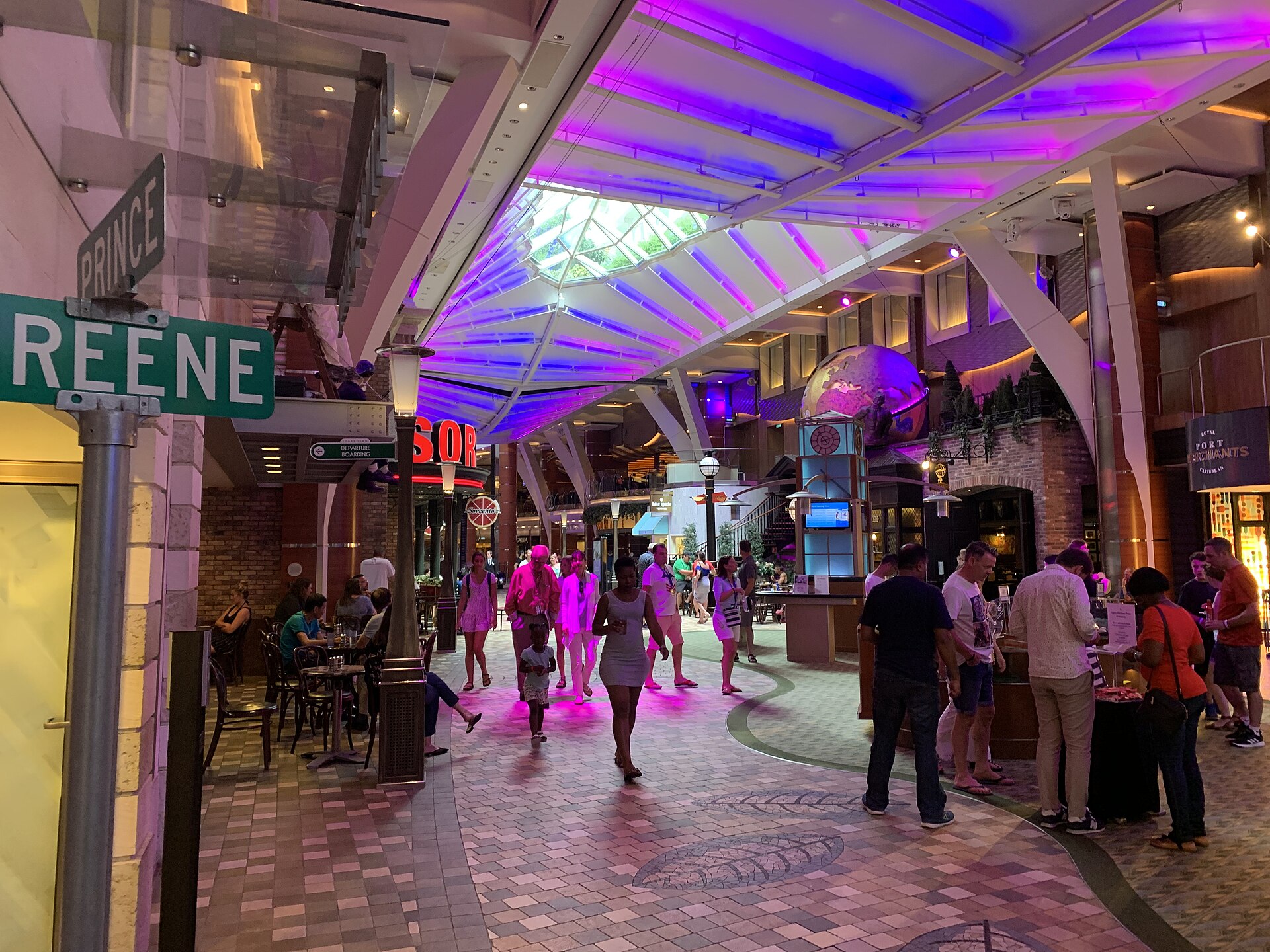 Colorful purple-lit Royal Promenade shopping street with bars and shops aboard Oasis of the Seas