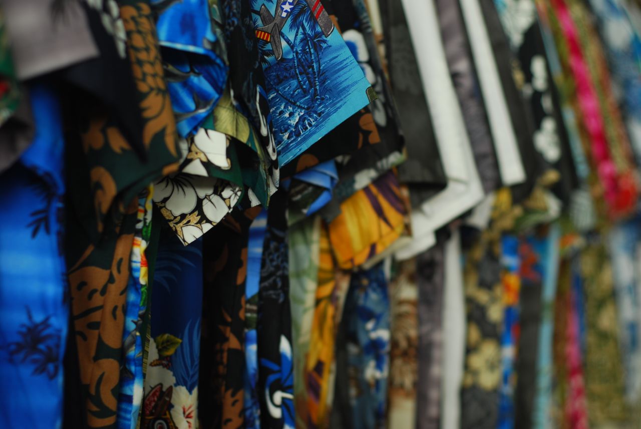 A rack of brightly coloured Hawaiian aloha shirts in blue, orange, pink and green prints