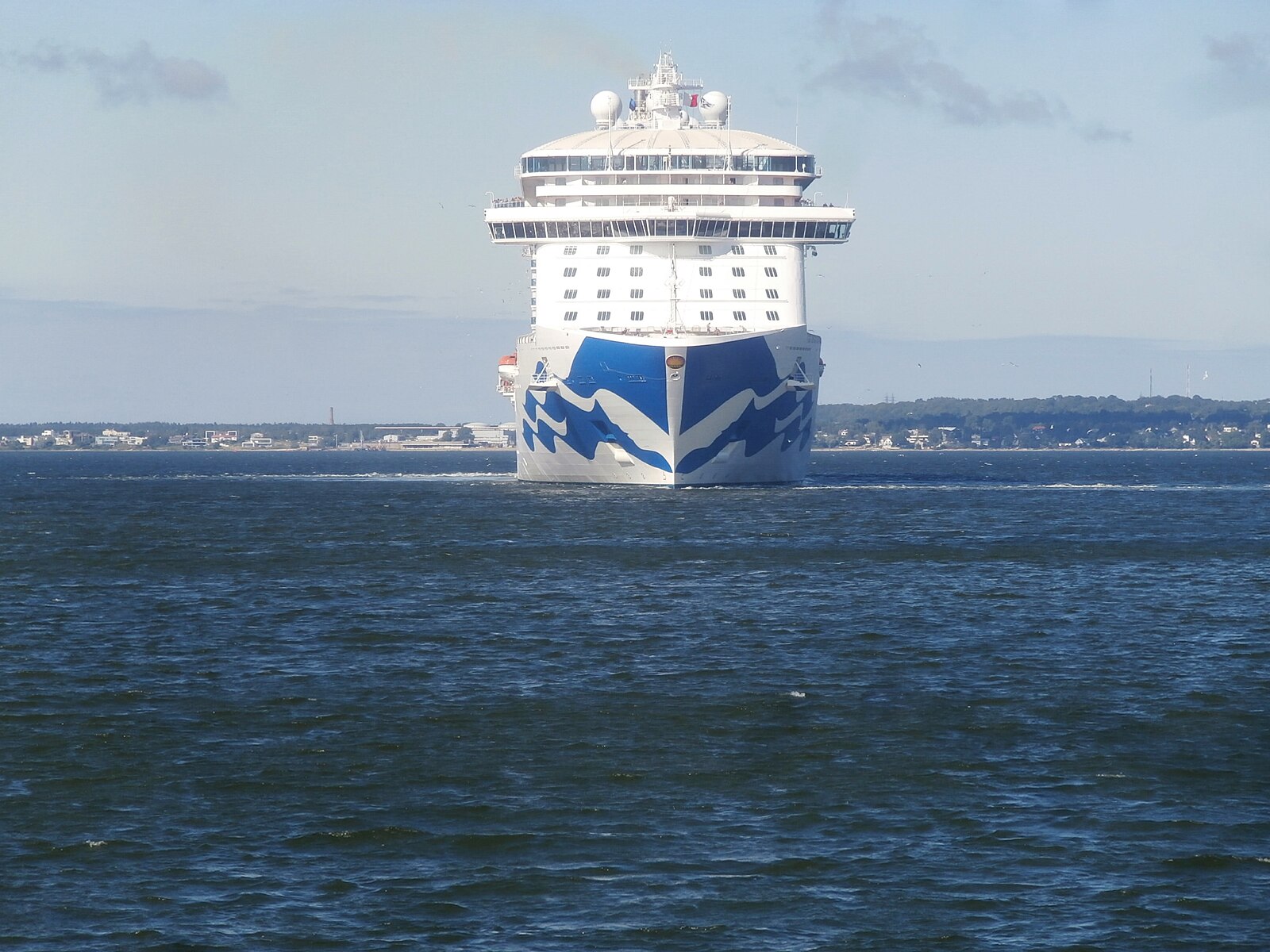 The bow of Regal Princess with the blue Princess seawitch logo, approaching across deep blue water