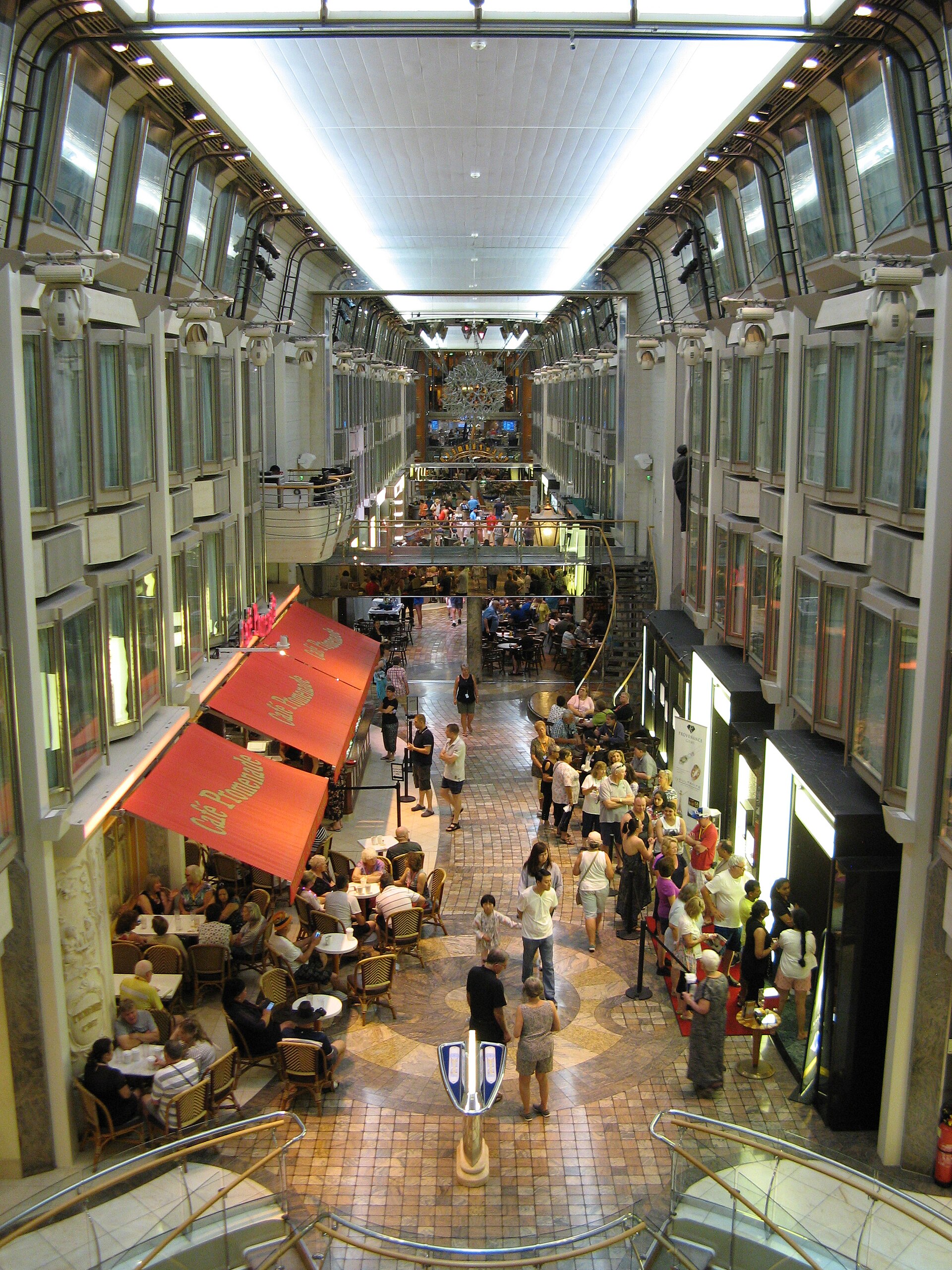 Shoppers and cafe tables along the Royal Promenade indoor street on a Royal Caribbean ship