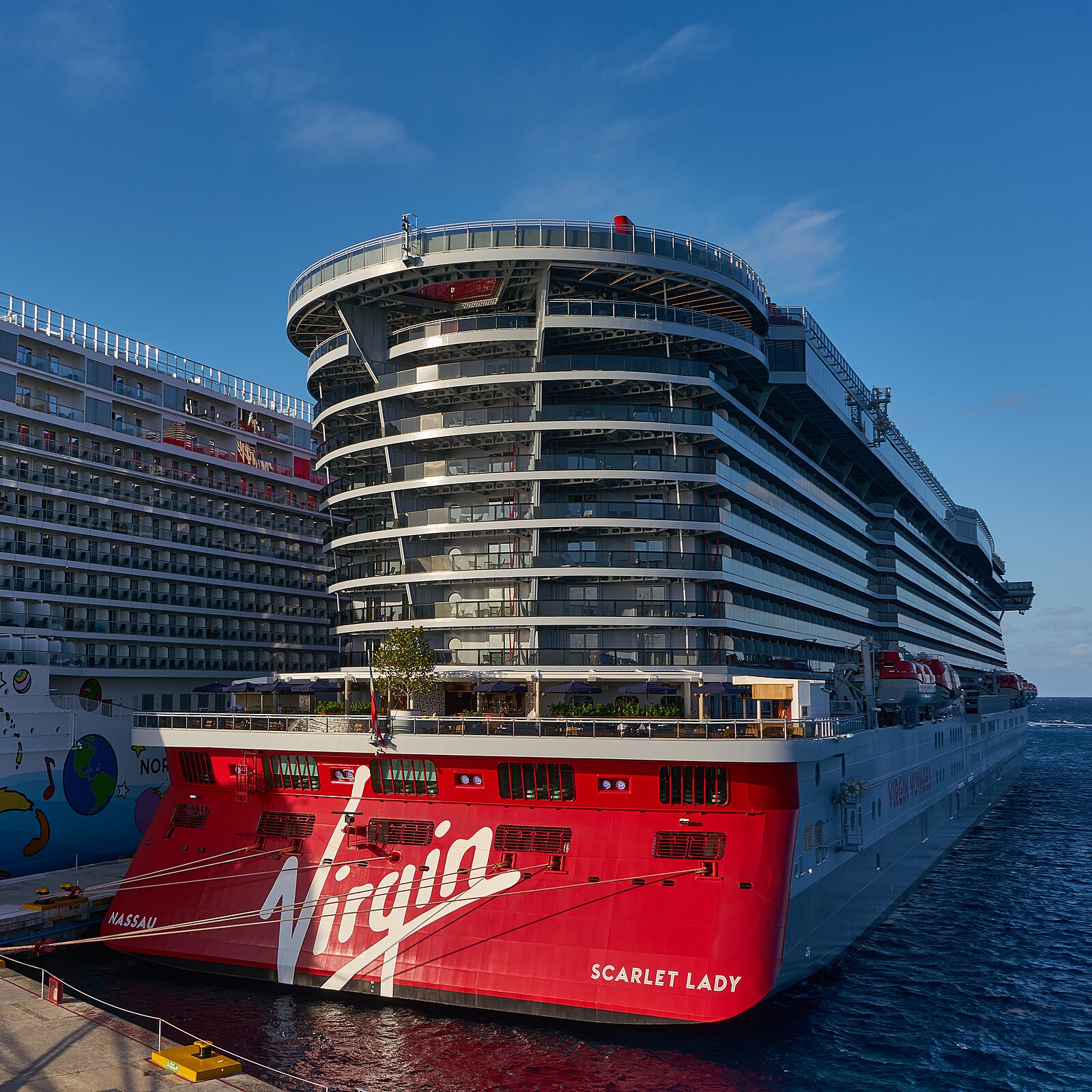 Red-hulled Virgin Voyages ship Scarlet Lady docked at a cruise pier in Cozumel, Mexico