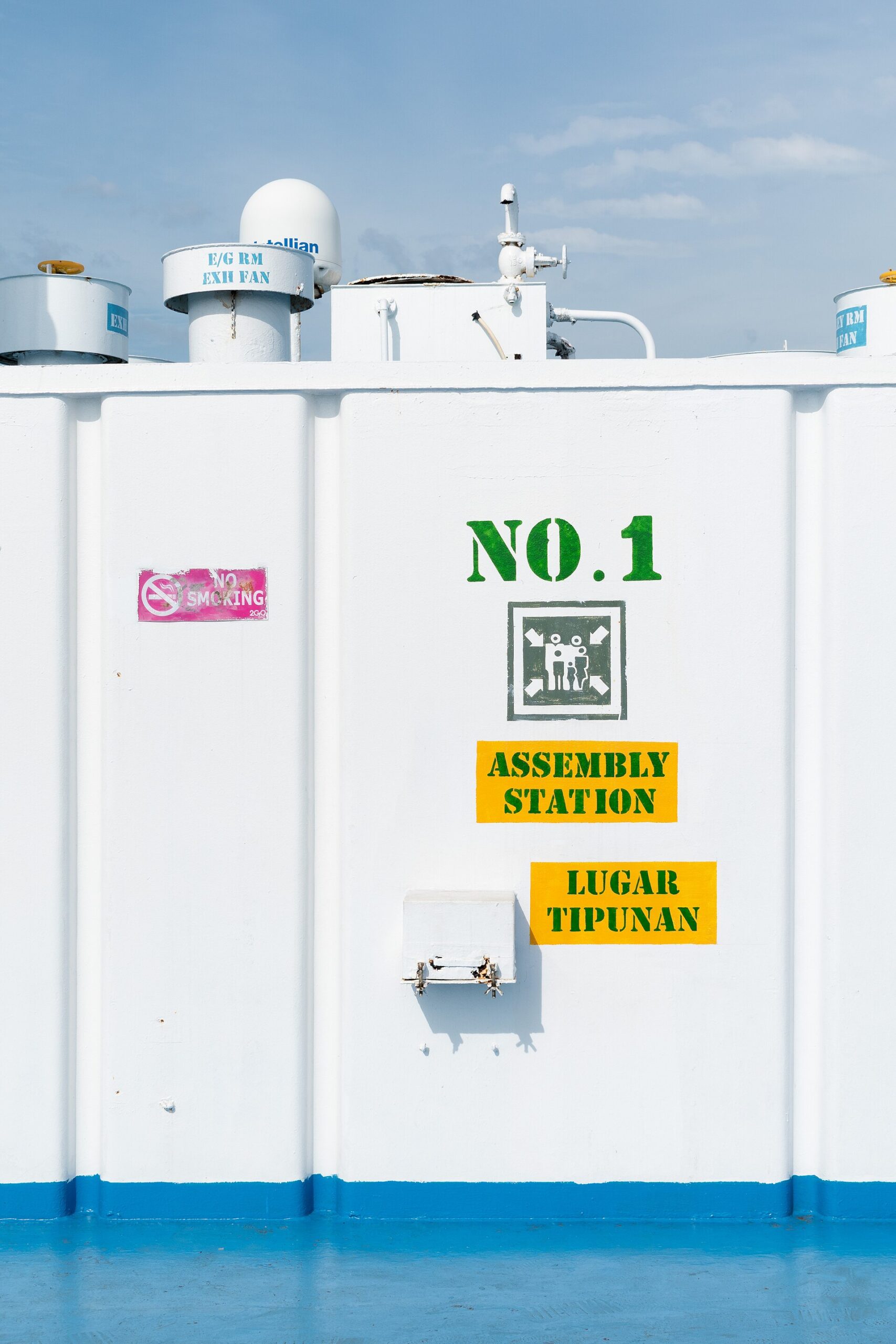 Green and yellow assembly station sign painted on a ship's deck