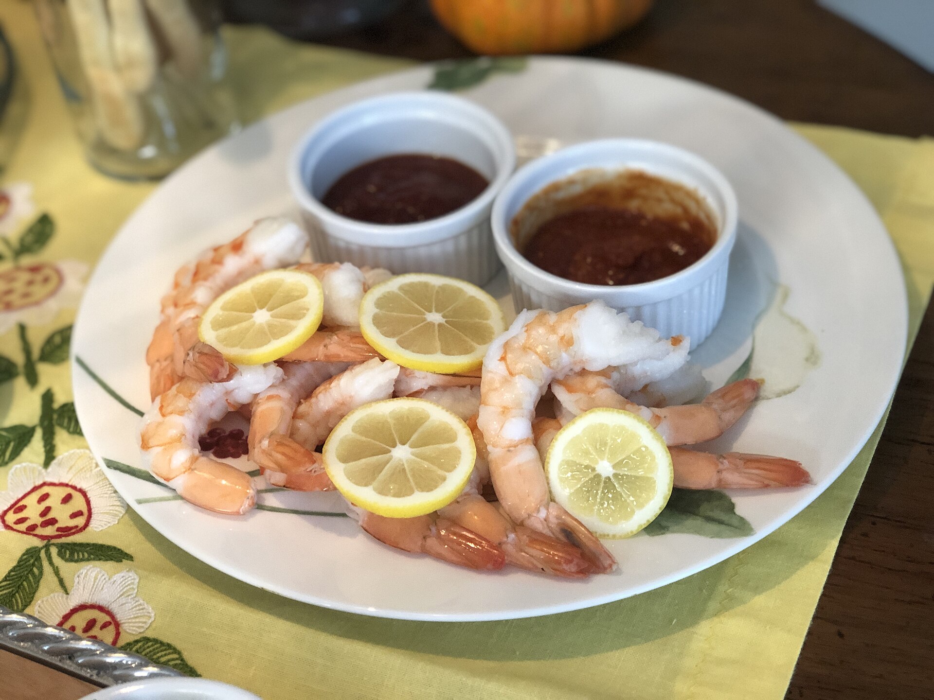 Plate of chilled shrimp with lemon slices and two pots of cocktail sauce