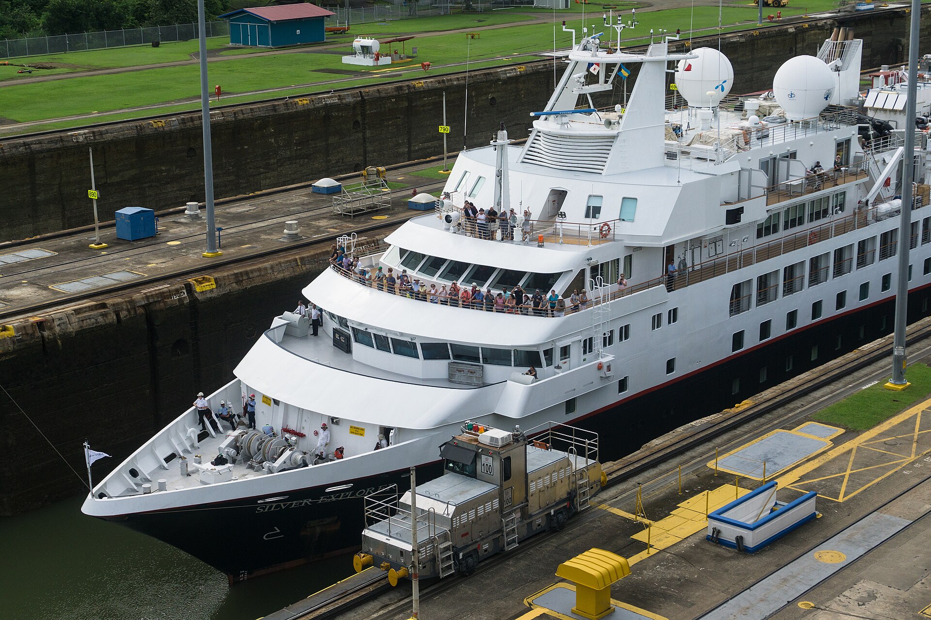 Expedition cruise ship Silver Explorer in the Miraflores Locks of the Panama Canal with passengers on the bow and a locomotive alongside