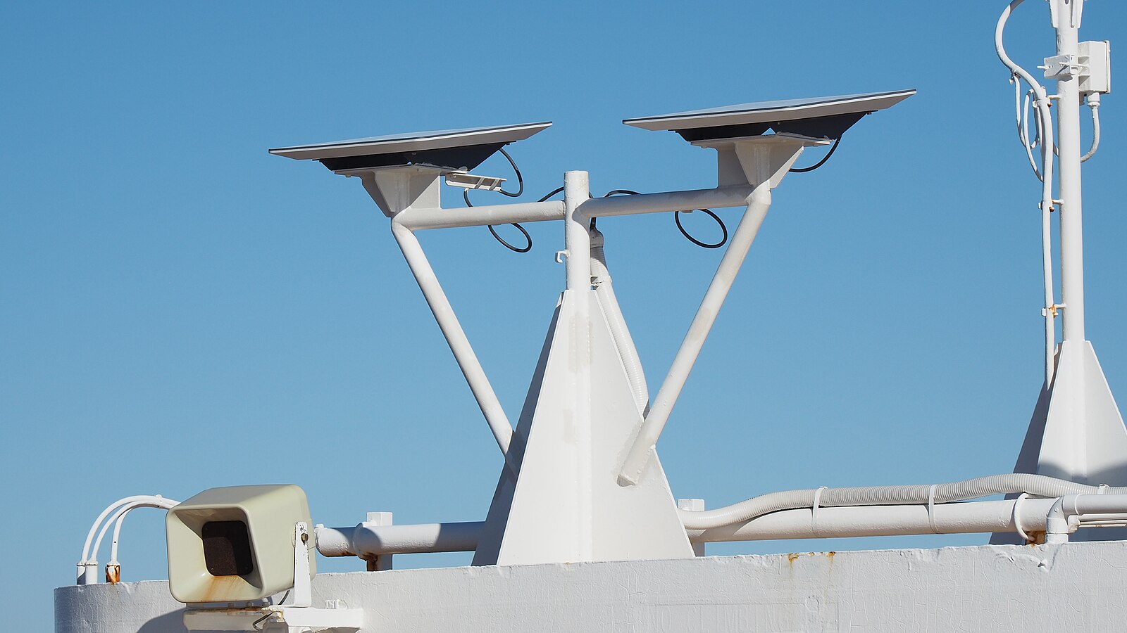 Two Starlink flat-panel satellite dishes mounted on a cruise ship mast against a blue sky