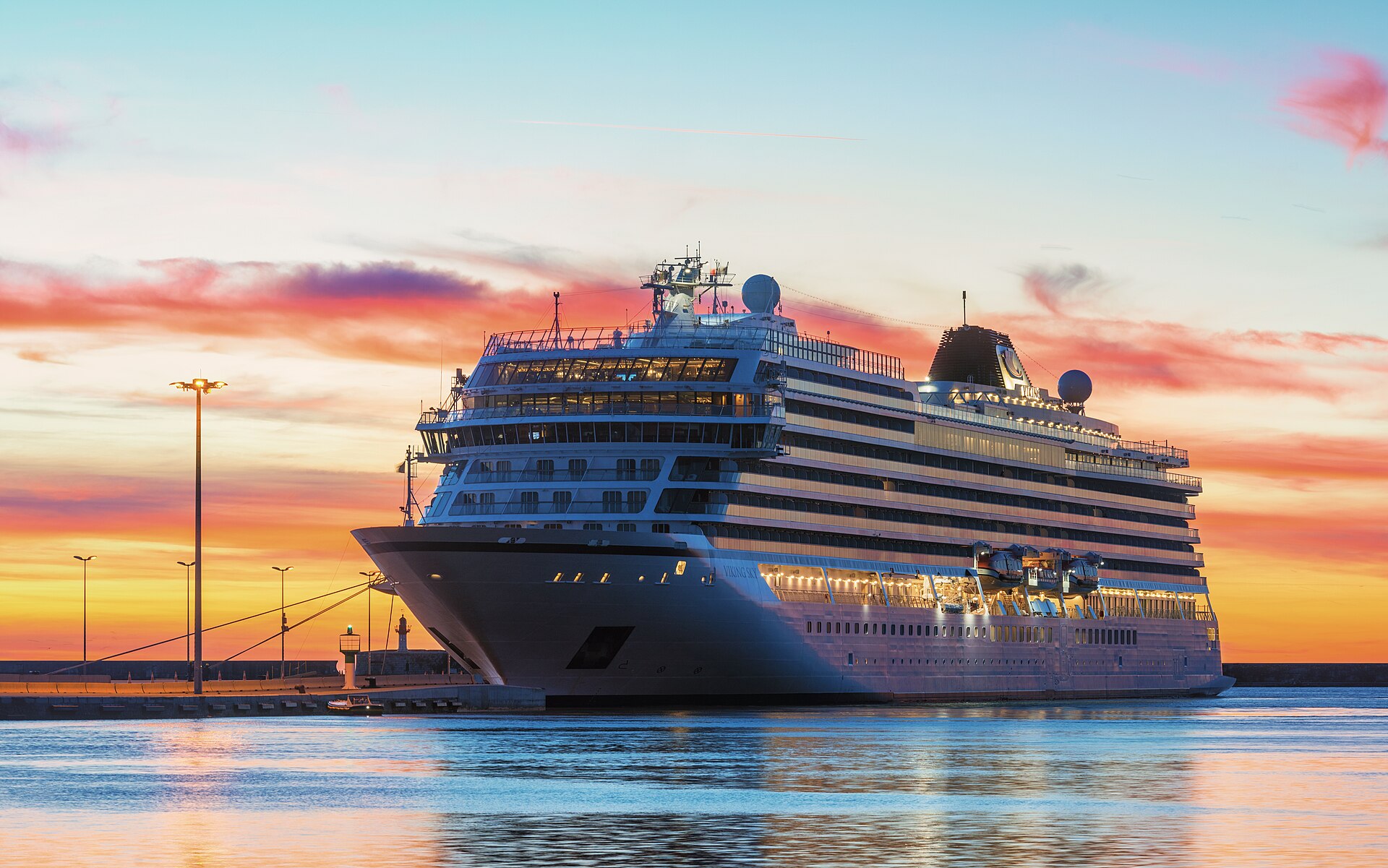 Viking Sky ocean cruise ship moored at Sete, France, under a pink and orange sunset sky