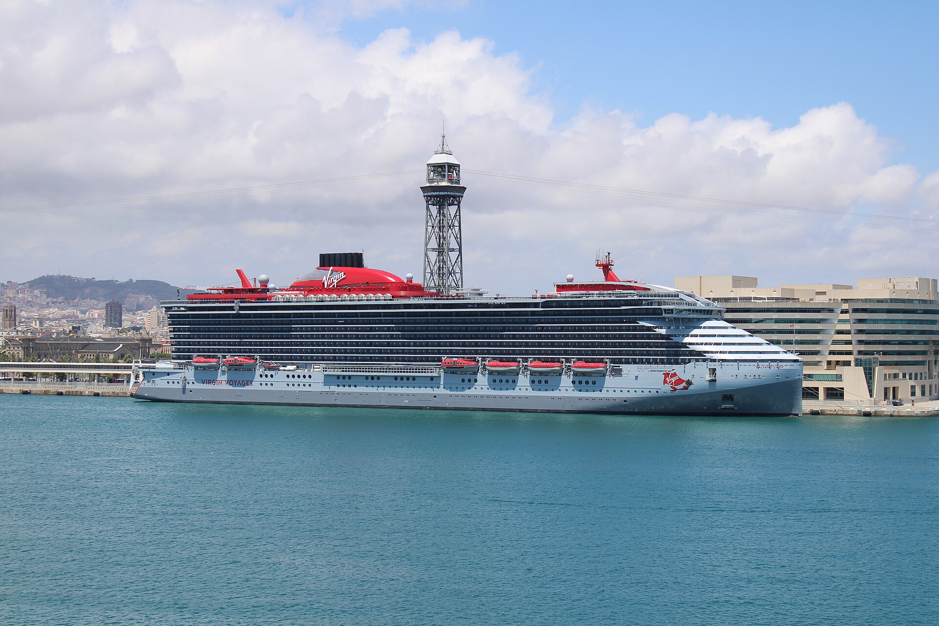 Virgin Voyages' Valiant Lady with its red funnel docked in Barcelona