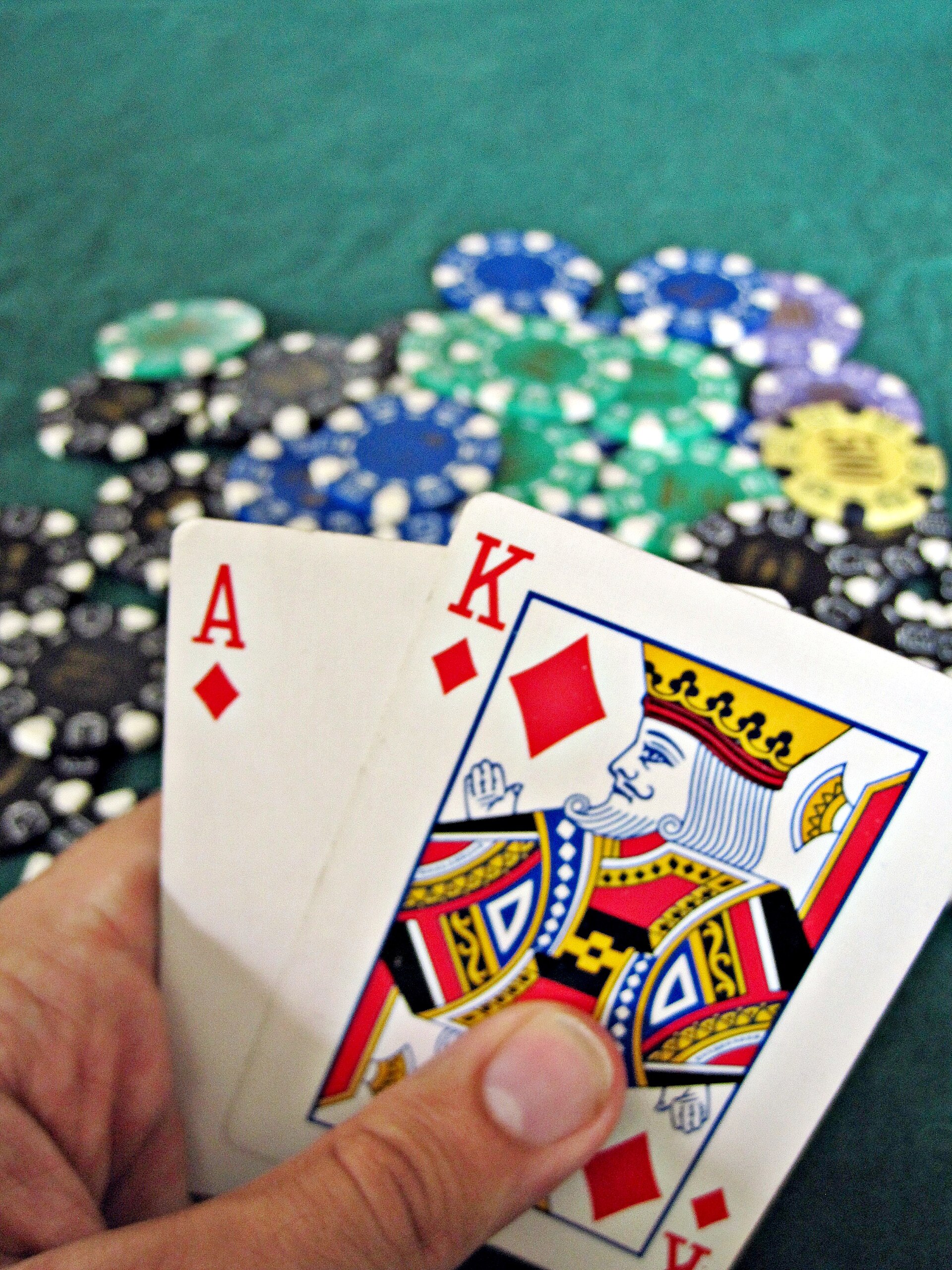 A player holding an ace and king of diamonds above a pile of colourful casino chips