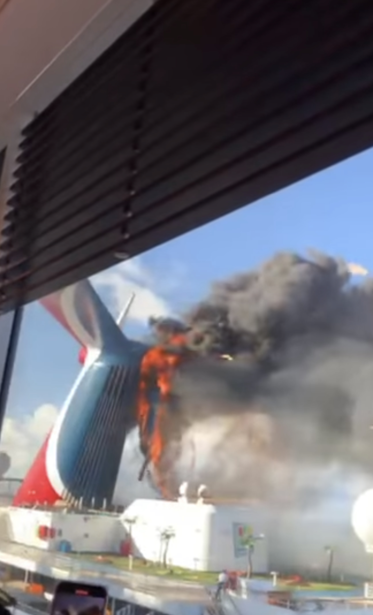 Flames and black smoke pouring from the starboard wing of Carnival Freedom's whale tail funnel at Grand Turk