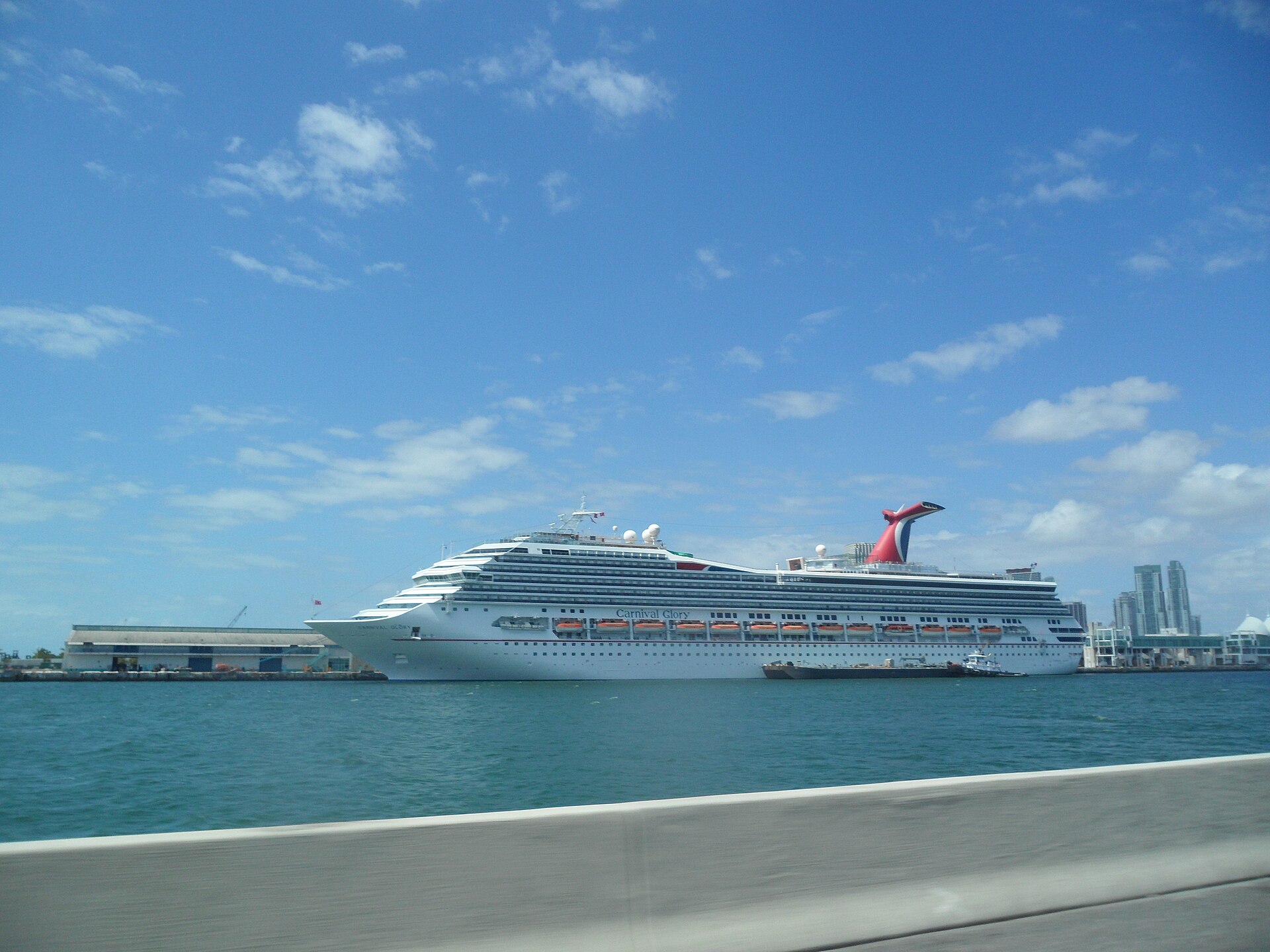 Carnival Glory with its red whale-tail funnel docked at PortMiami under a wide blue sky