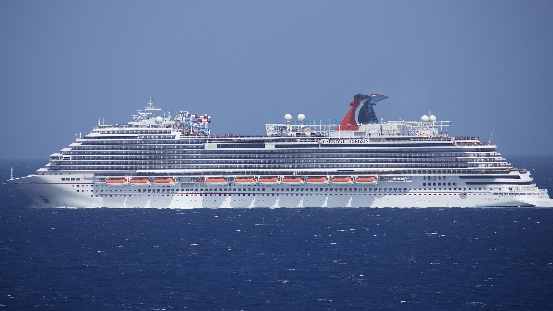 Carnival Horizon sailing on deep blue water off Grand Turk, with its red, white and blue whale-tail funnel