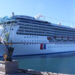 Carnival Spirit cruise ship docked beside a waterfront promenade under a clear blue sky