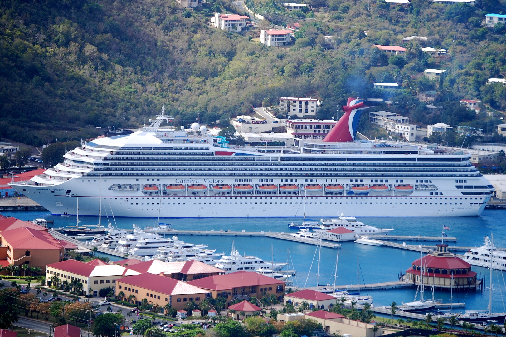 Carnival Victory docked in Charlotte Amalie, St. Thomas, above a marina of yachts and red-roofed buildings