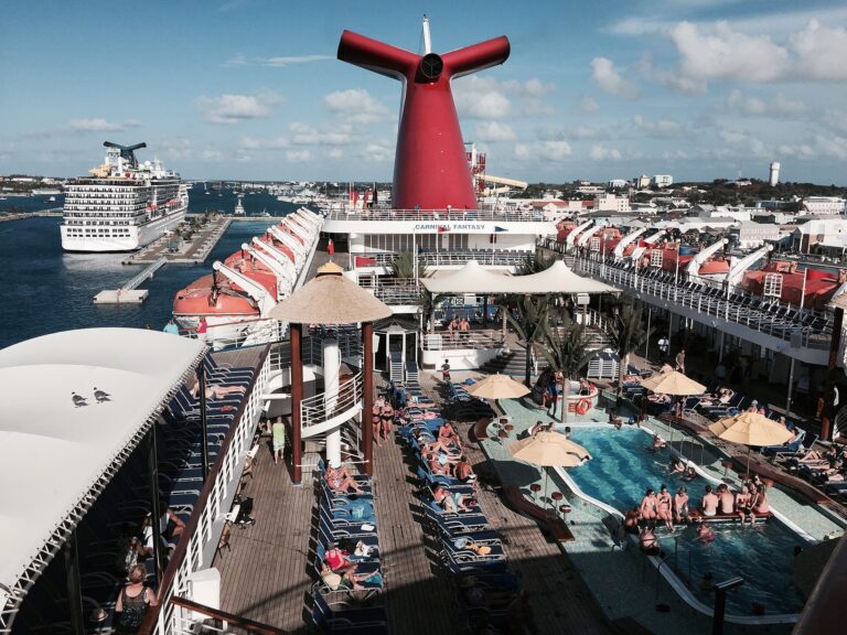 Guests around the Lido deck pool of Carnival Fantasy as the ship leaves Nassau, with Carnival Pride docked behind