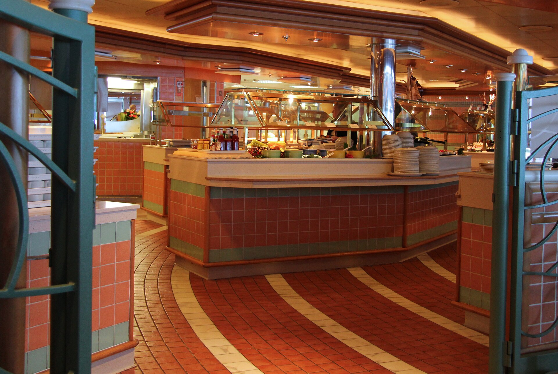 Empty cruise ship buffet with terracotta and green tiled counters and a red patterned floor on Golden Princess