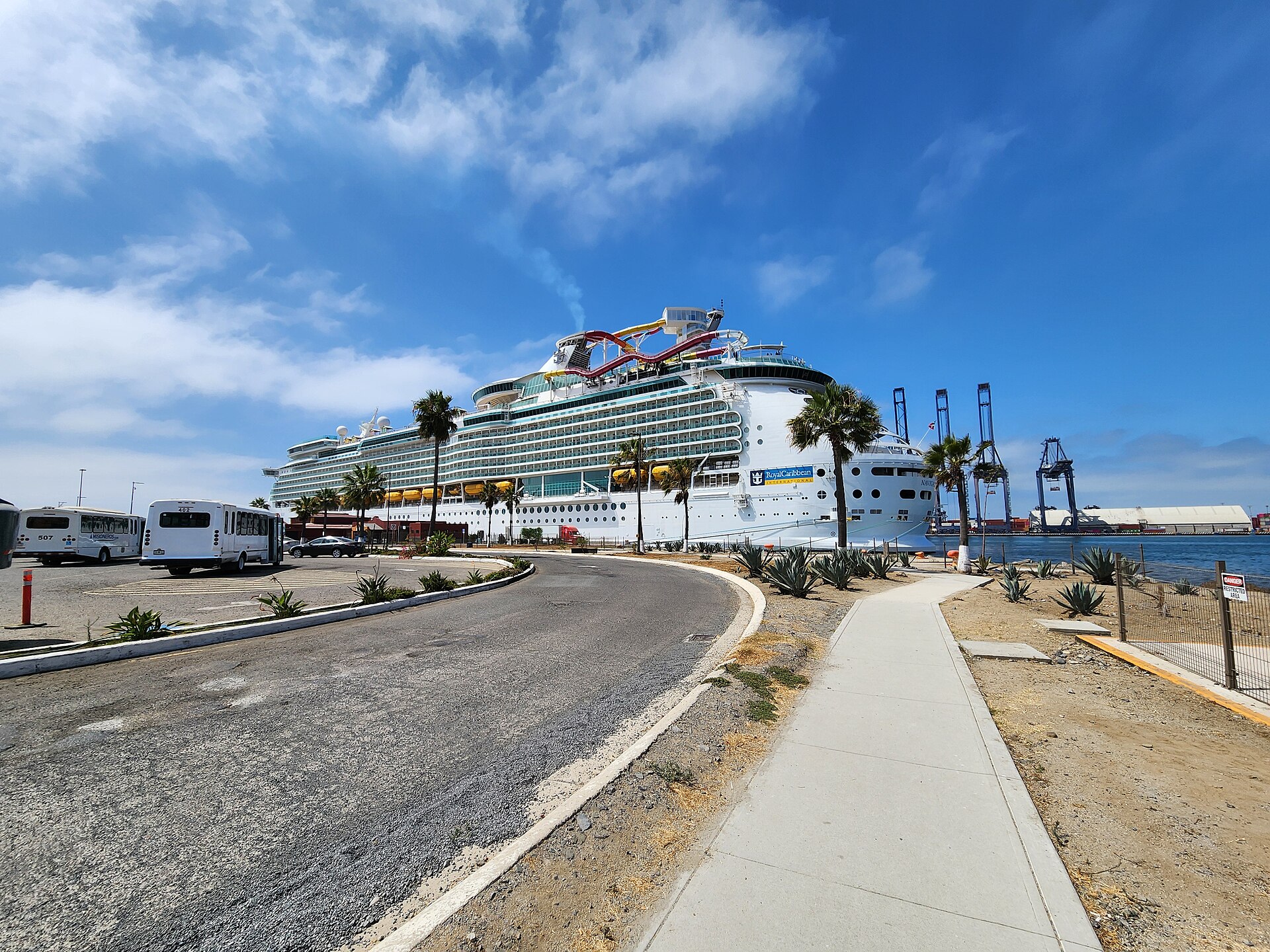 Navigator of the Seas docked at the cruise port in Ensenada, Mexico, with palm trees and blue sky