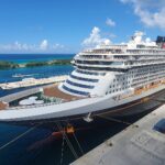 Disney Wish docked in Nassau under a bright blue sky with turquoise water and white clouds