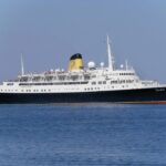 The classic liner Funchal, with a navy hull, white superstructure and yellow funnel, sailing on a bright blue sea
