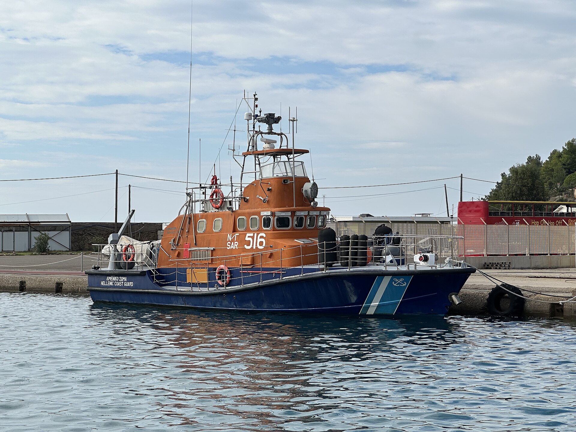 An orange and blue Hellenic Coast Guard search-and-rescue lifeboat, numbered SAR 516, moored at a quay
