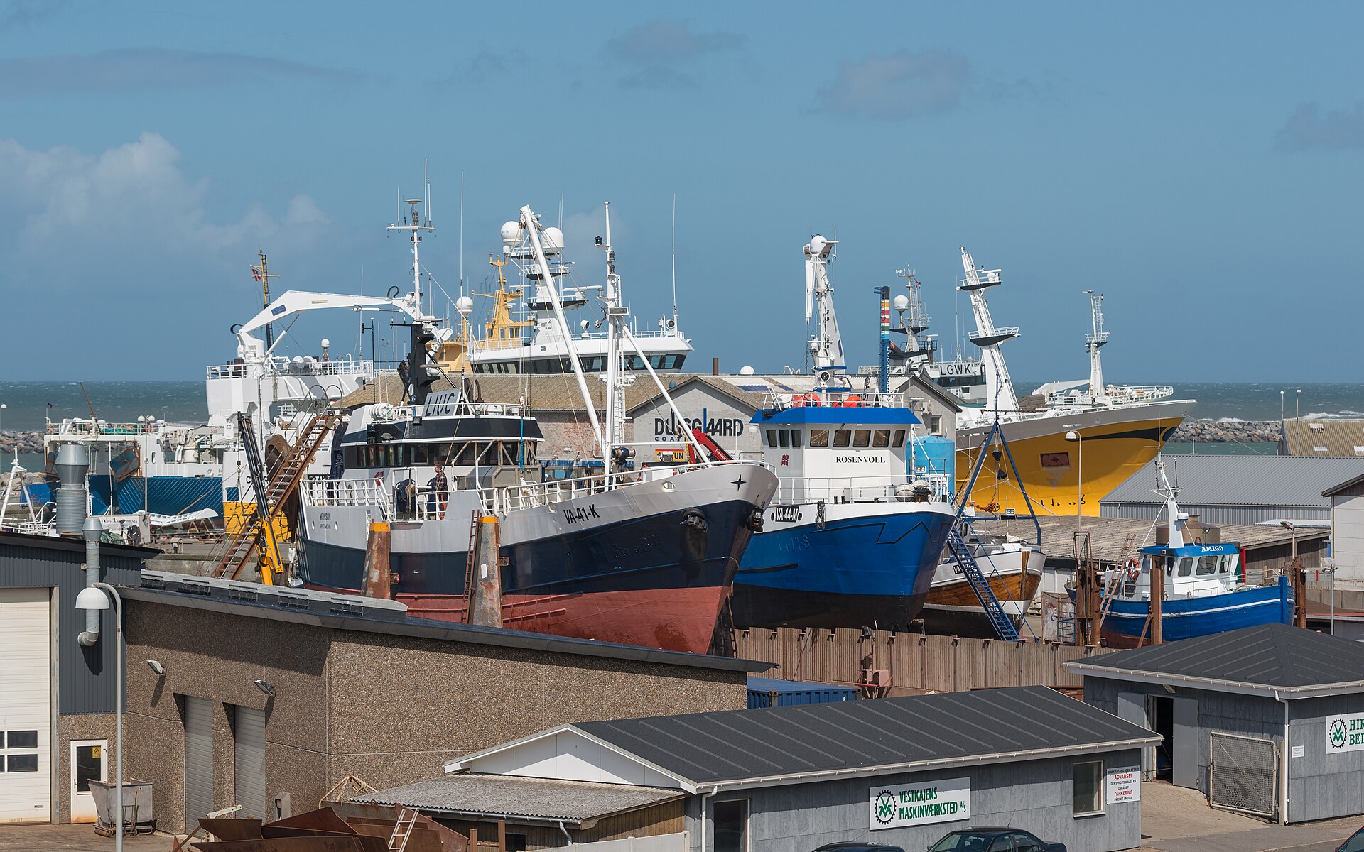 Colourful fishing boats moored in Hirtshals harbour, Denmark, under a blue sky