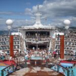 Sunbathers and swimmers around the Pool Bar on the sunny pool deck of Royal Caribbean's Independence of the Seas
