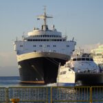 The white and blue catamaran King of Rhodes approaching the quay beside the much larger cruise ship Blue Sapphire in the Port of Rhodes, evening light